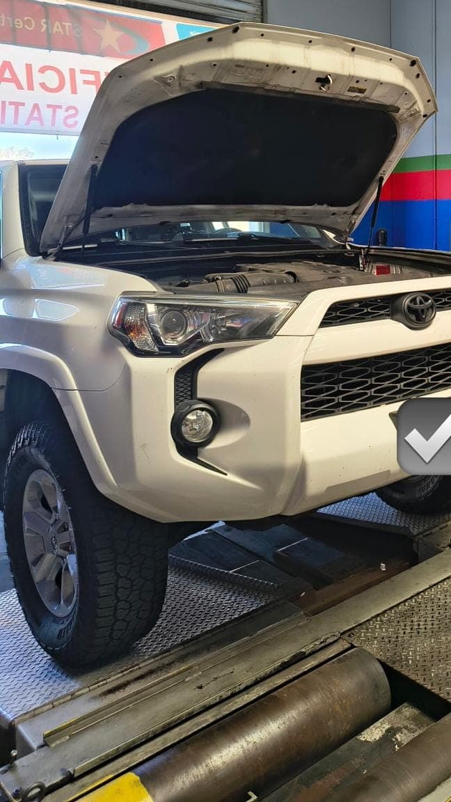 White Toyota 4Runner on the dynamometer rollers with the hood up