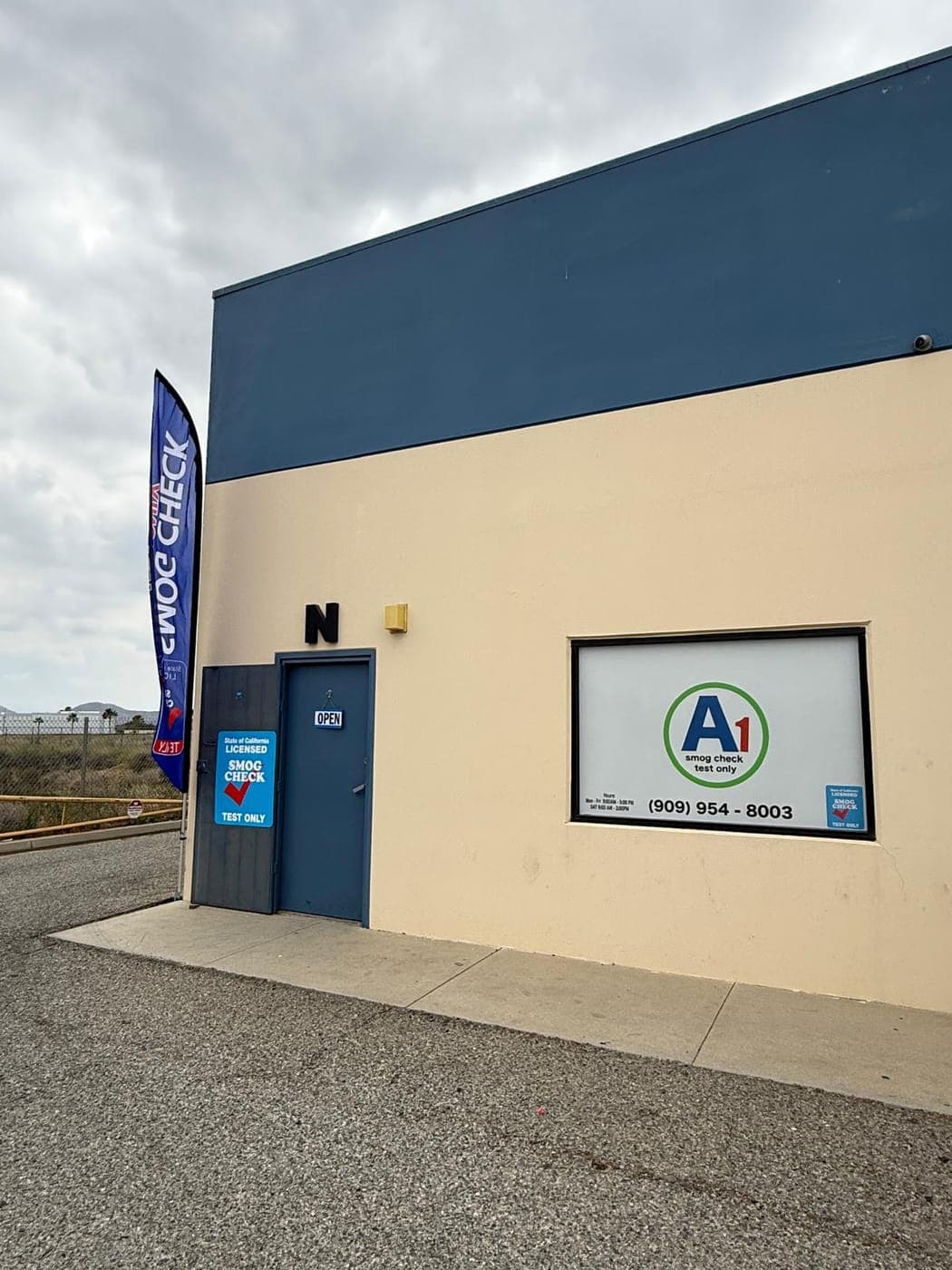 Front of A1 Smog Check Unit N: blue door with an OPEN sign, State of California licensed sign, and the A1 window sign with the phone number