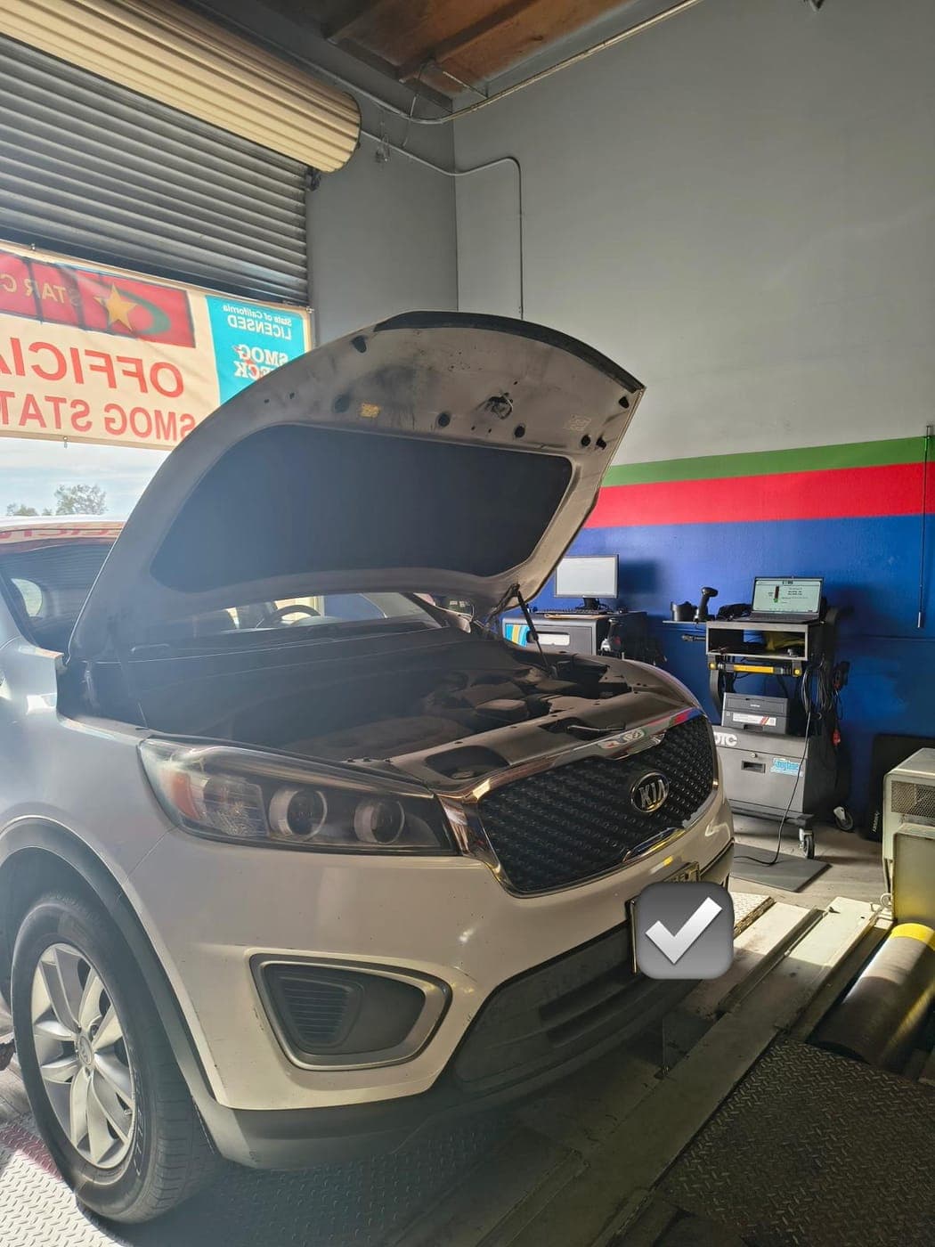White Kia Sorento mid-test with the hood raised and the analyzer screen behind it